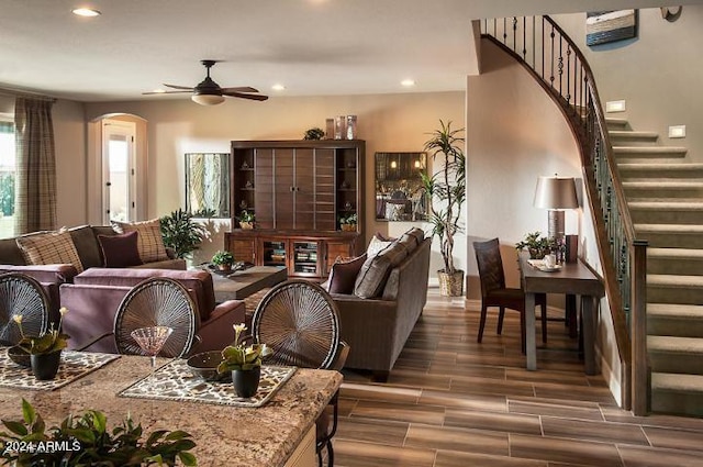 living area with ceiling fan, stairway, arched walkways, and wood finish floors