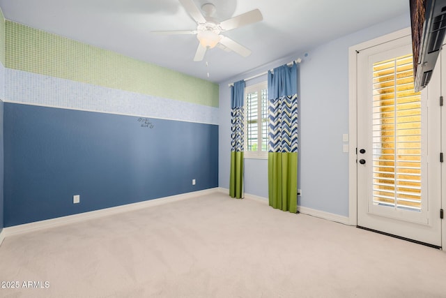 empty room with carpet floors, a ceiling fan, and baseboards