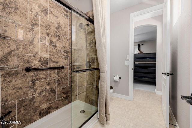 bathroom featuring a stall shower, toilet, and baseboards