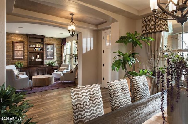 dining area with a tray ceiling, arched walkways, and wood finished floors