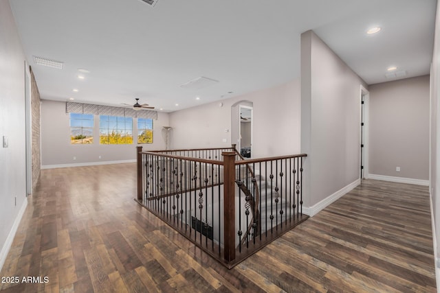 corridor with baseboards, arched walkways, wood finished floors, and recessed lighting