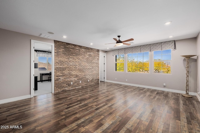 unfurnished living room with baseboards, visible vents, brick wall, and wood finished floors