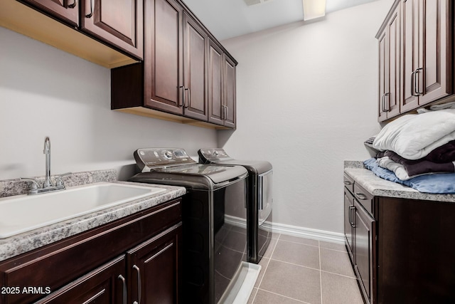 laundry area featuring cabinet space, light tile patterned floors, baseboards, washer and clothes dryer, and a sink