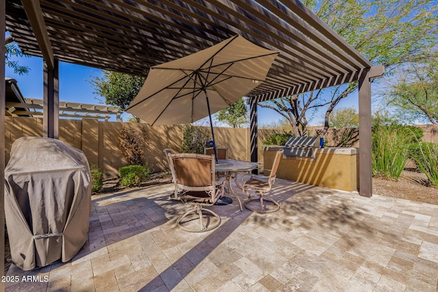 view of patio / terrace with exterior kitchen, outdoor dining area, a fenced backyard, and a pergola