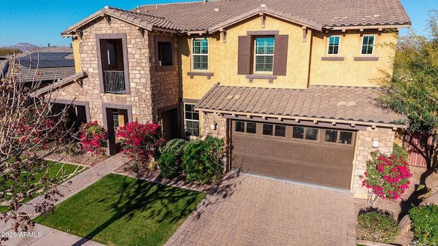 view of front of property with a garage, stone siding, a tile roof, and stucco siding