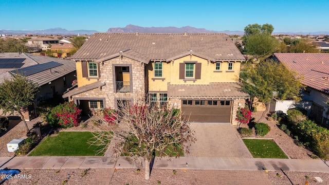 view of front of home featuring a garage, stone siding, decorative driveway, a mountain view, and stucco siding