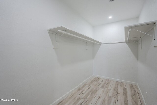 walk in closet with light hardwood / wood-style floors