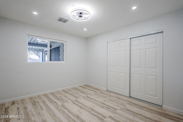 unfurnished bedroom with light hardwood / wood-style floors and a closet