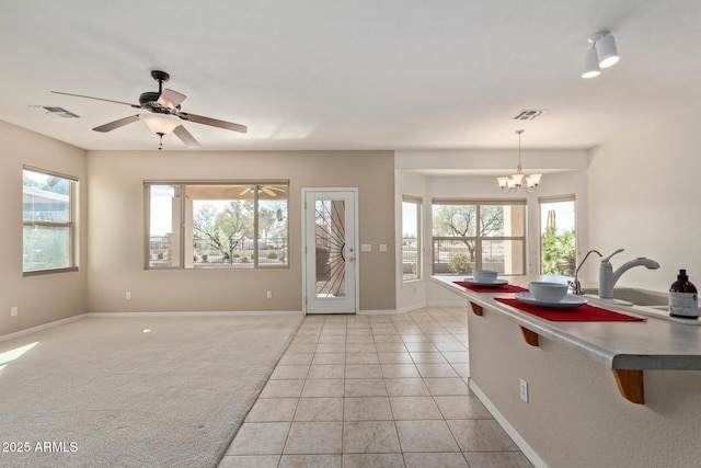 kitchen with hanging light fixtures, ceiling fan with notable chandelier, sink, and light tile patterned floors