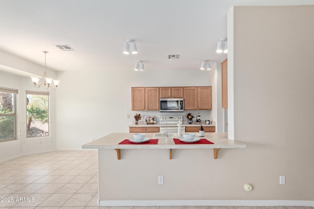 kitchen featuring sink, a kitchen breakfast bar, a notable chandelier, pendant lighting, and electric stove