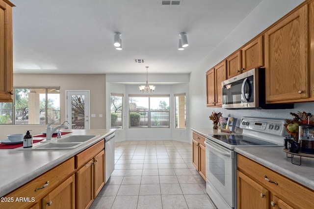 kitchen with appliances with stainless steel finishes, sink, hanging light fixtures, and a wealth of natural light