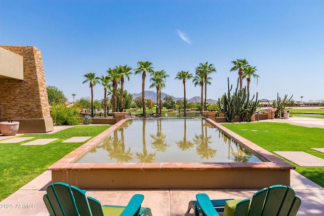 view of pool with a mountain view and a lawn