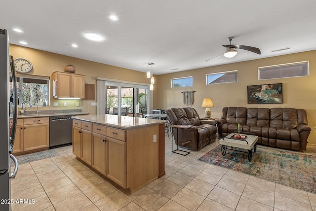 kitchen with dishwasher, sink, a kitchen island, and light tile patterned floors