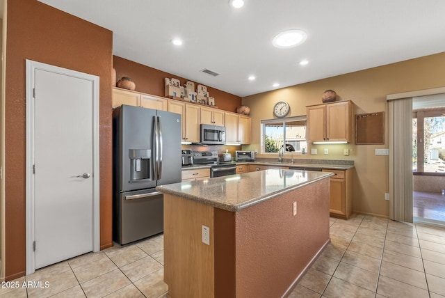 kitchen with light brown cabinetry, stainless steel appliances, a center island, and light tile patterned flooring