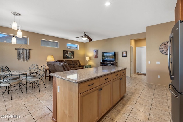 kitchen featuring light tile patterned floors, decorative light fixtures, stainless steel refrigerator, and a kitchen island