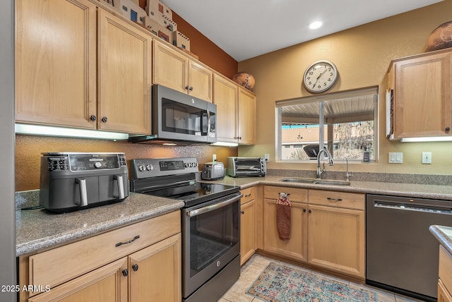 kitchen with light tile patterned flooring, appliances with stainless steel finishes, sink, and light brown cabinets