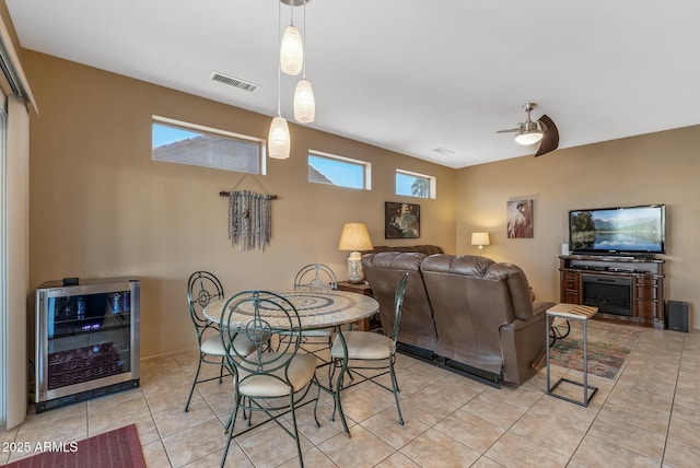 tiled dining room featuring a healthy amount of sunlight, beverage cooler, and ceiling fan