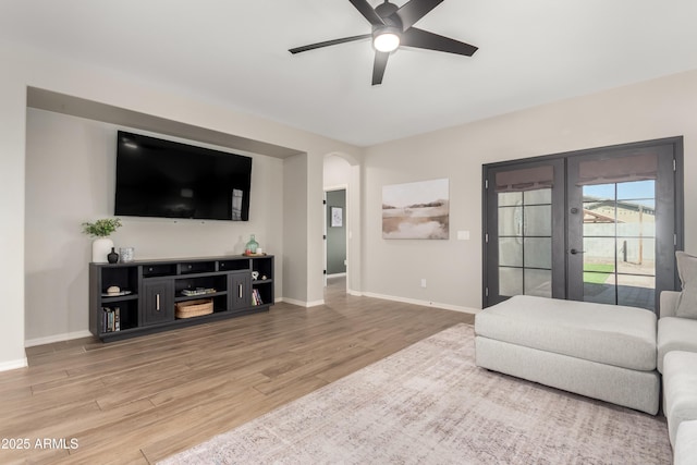 living room with a ceiling fan, baseboards, and wood finished floors