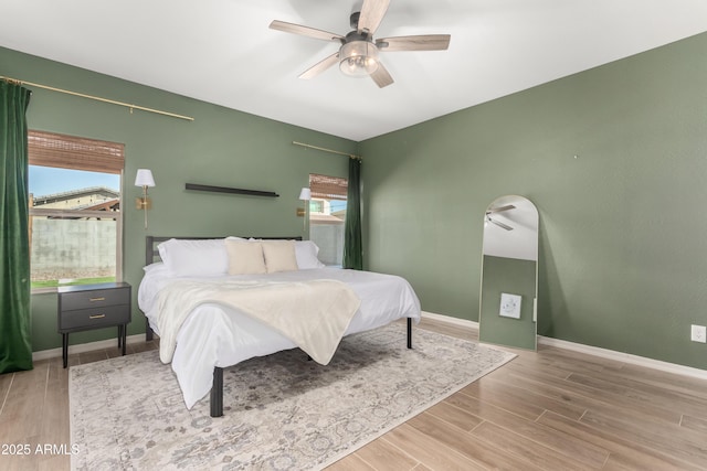 bedroom with ceiling fan, wood finished floors, and baseboards