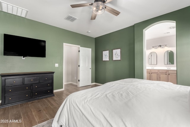 bedroom featuring dark wood-style floors, baseboards, visible vents, and connected bathroom