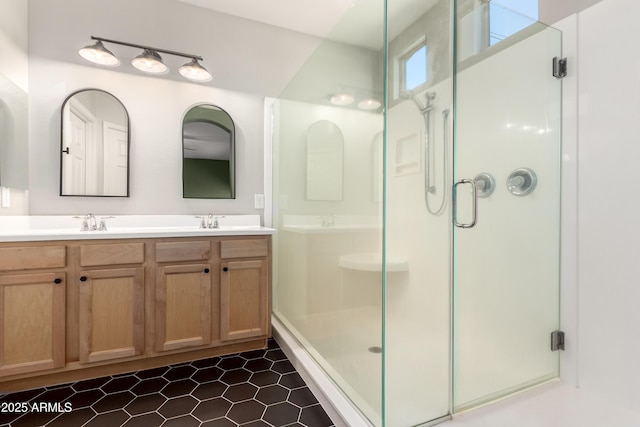 bathroom featuring double vanity, a stall shower, and a sink