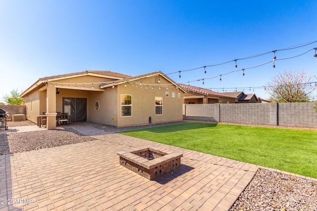 rear view of house with a fenced backyard, a fire pit, a lawn, stucco siding, and a patio area