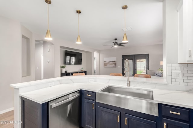 kitchen featuring backsplash, open floor plan, a sink, blue cabinets, and dishwasher