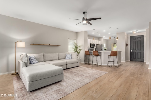 living room with light wood-type flooring, ceiling fan, baseboards, and recessed lighting