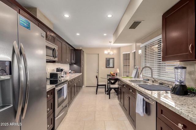 kitchen featuring visible vents, appliances with stainless steel finishes, light tile patterned flooring, dark brown cabinetry, and a sink