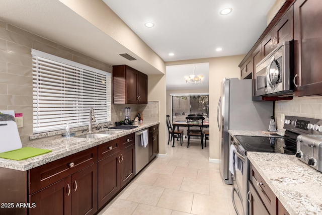 kitchen featuring light tile patterned floors, a sink, stainless steel appliances, dark brown cabinets, and backsplash