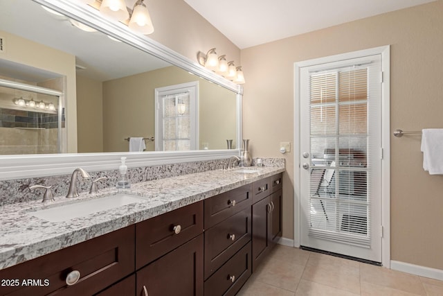 bathroom with double vanity, tile patterned flooring, baseboards, and a sink