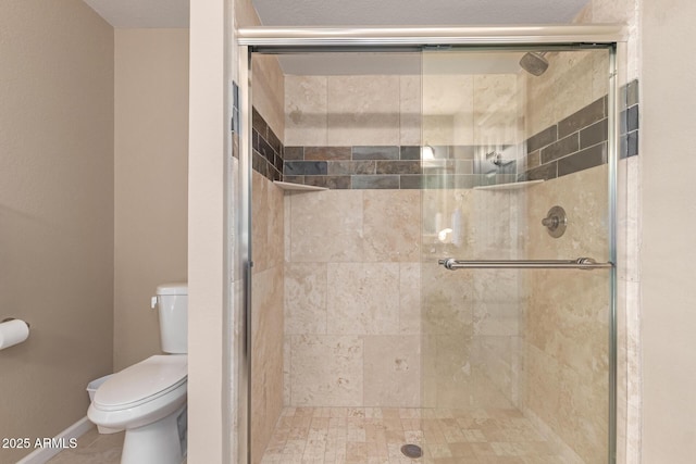 bathroom with toilet, a stall shower, and baseboards