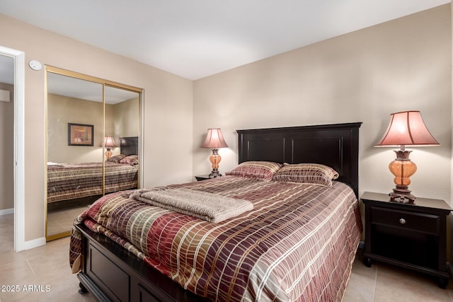 bedroom featuring a closet, light tile patterned flooring, and baseboards