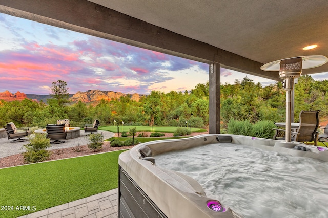 patio terrace at dusk with an outdoor fire pit and a lawn