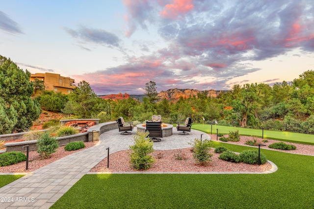 view of property's community featuring a fire pit, a patio area, and a lawn