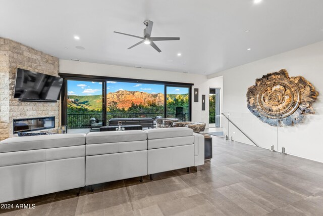 living room with ceiling fan and a stone fireplace