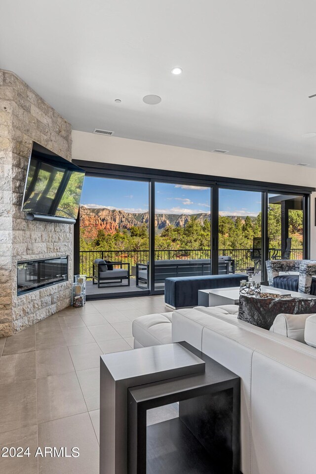 unfurnished living room with a stone fireplace and light tile patterned flooring