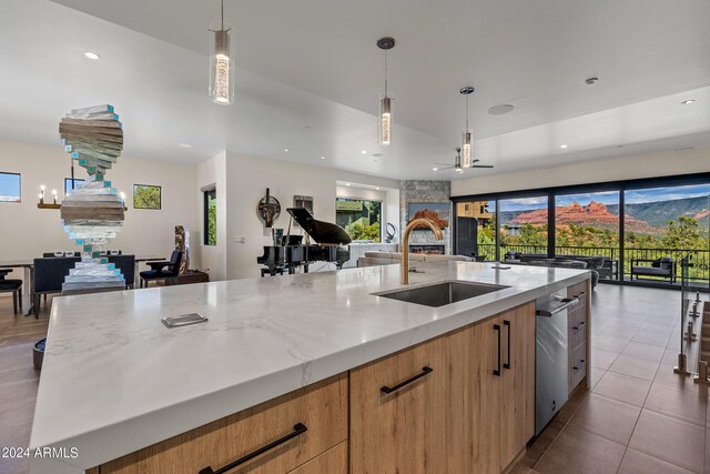 kitchen featuring hanging light fixtures, a fireplace, light stone countertops, sink, and a large island