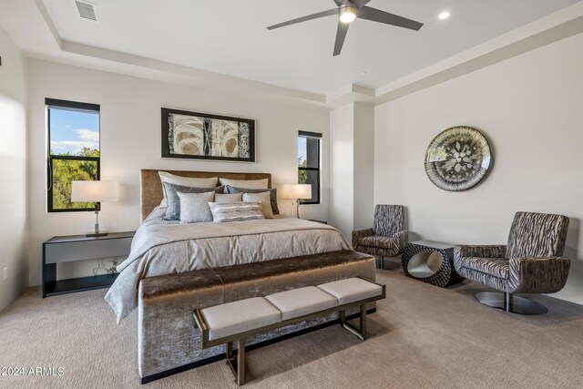 carpeted bedroom featuring a tray ceiling and ceiling fan