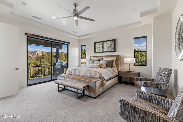 bedroom with a tray ceiling, ceiling fan, access to exterior, and light carpet