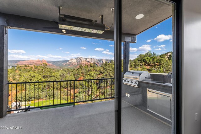 balcony featuring a mountain view, grilling area, an outdoor kitchen, and sink