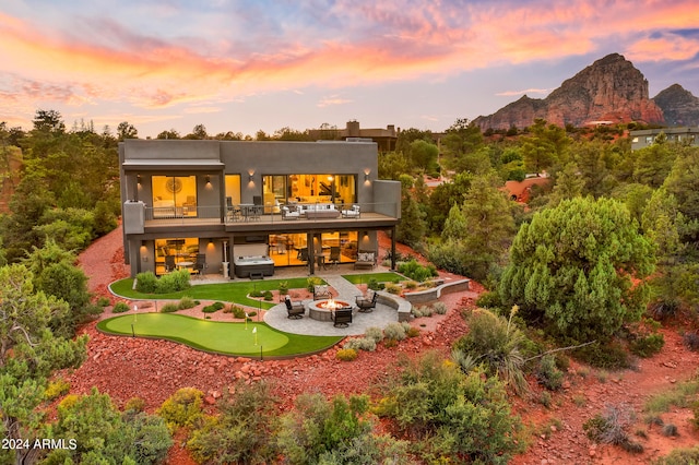 back house at dusk featuring a patio area, a mountain view, and an outdoor living space with a fire pit