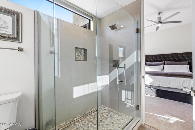 bathroom with toilet, an enclosed shower, and ceiling fan