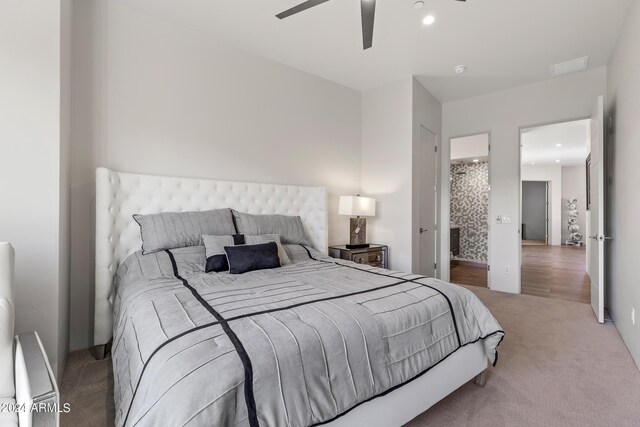 bedroom featuring ceiling fan, light colored carpet, and connected bathroom