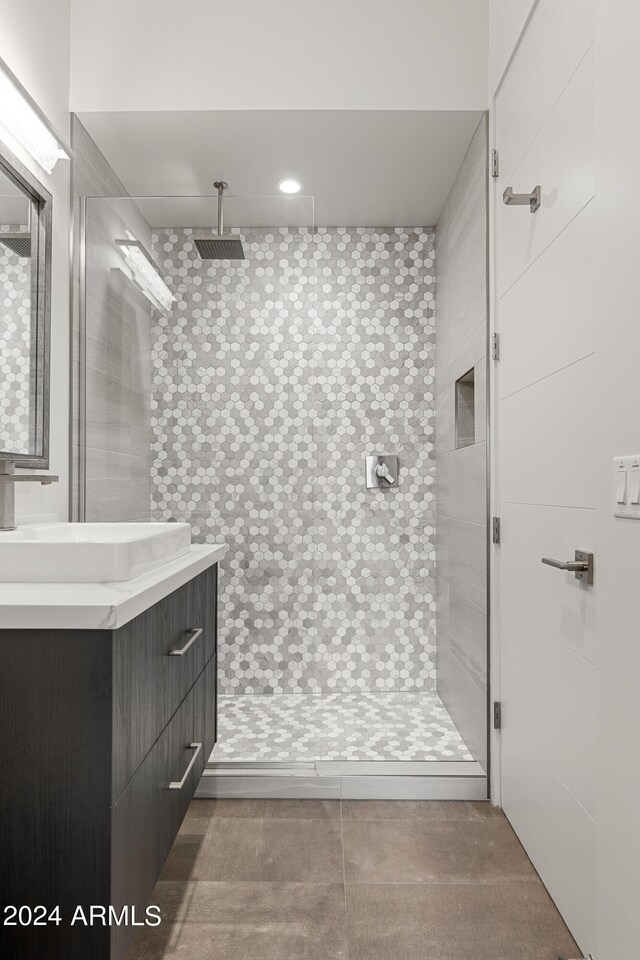 bathroom with tiled shower, vanity, and tile walls