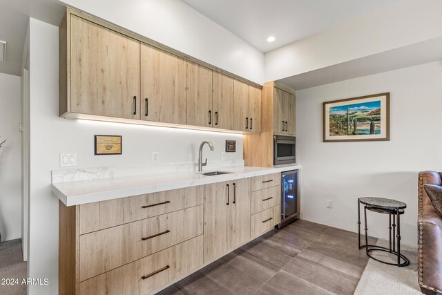 kitchen with light brown cabinets, stainless steel microwave, wine cooler, and sink