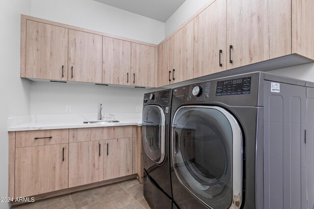 laundry area featuring cabinets, washer and clothes dryer, sink, and light tile patterned floors