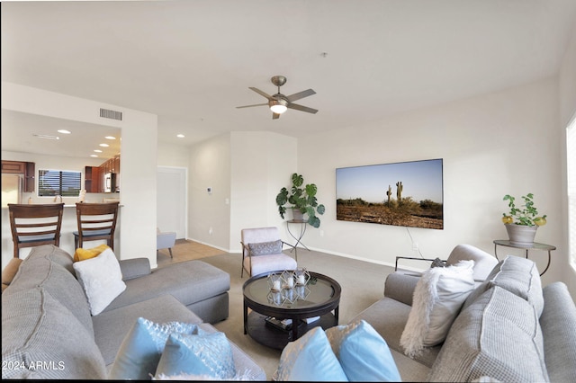 living room featuring a ceiling fan, visible vents, baseboards, recessed lighting, and light colored carpet