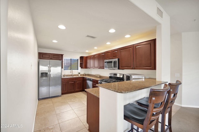 kitchen featuring stone countertops, visible vents, a peninsula, and stainless steel appliances