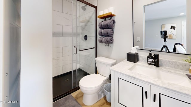 bathroom featuring vanity, a shower with door, and toilet